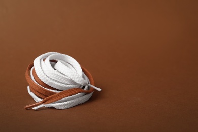 Photo of Different shoe laces on brown background. Space for text