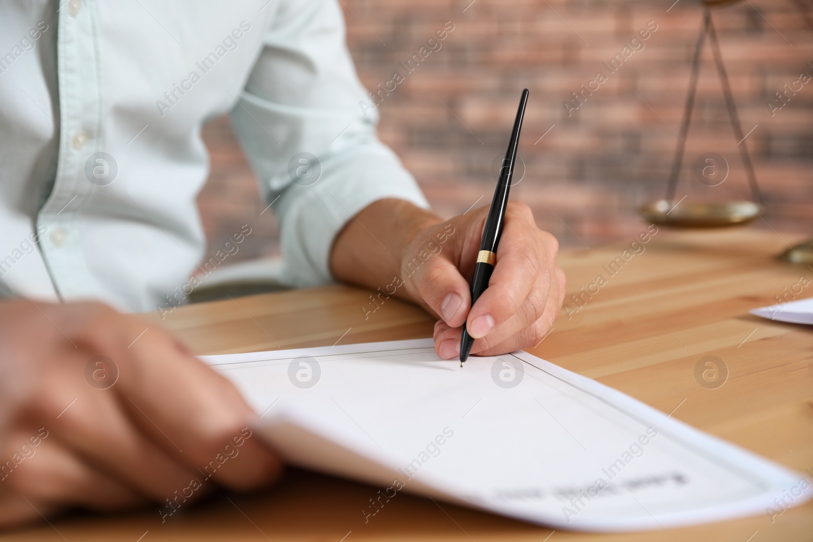 Photo of Male notary signing document at table in office, closeup