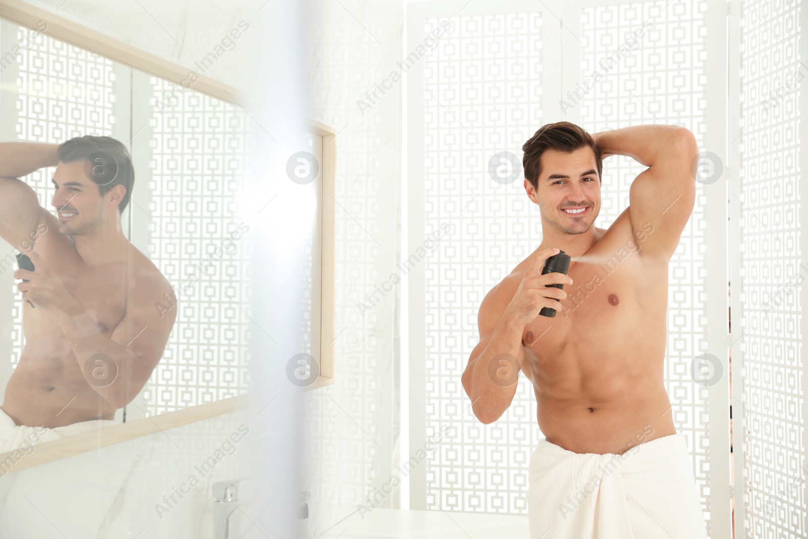 Photo of Handsome young man applying deodorant in bathroom