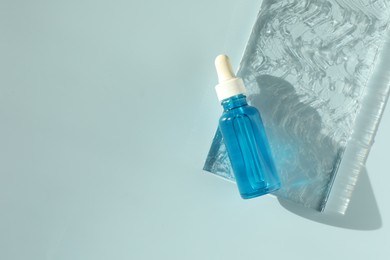 Photo of Bottle of cosmetic serum on light blue background, top view. Space for text