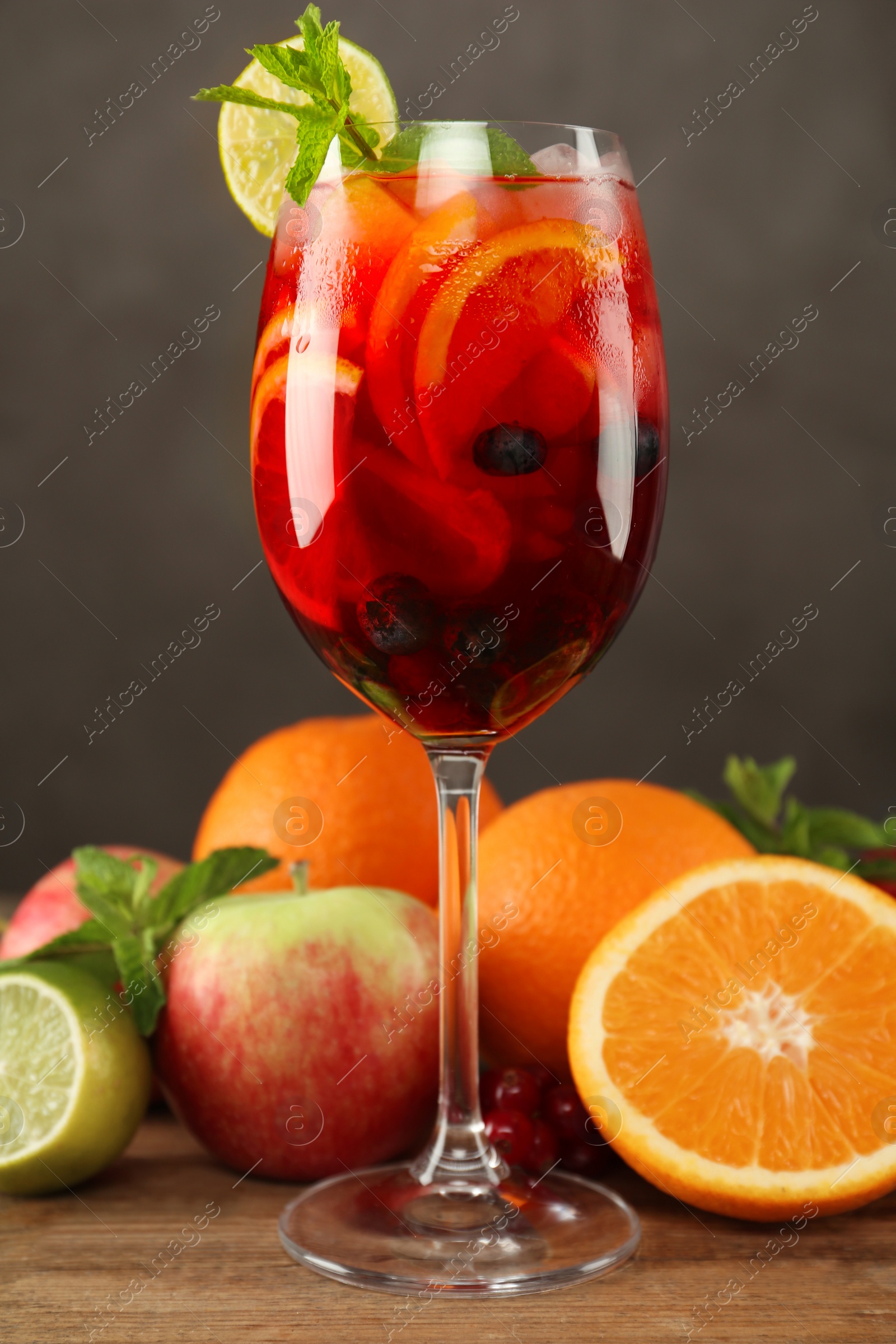 Photo of Glass of Red Sangria and fruits on wooden table