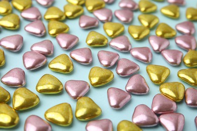 Many delicious heart shaped candies on light blue background