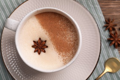 Cup of delicious eggnog with anise on wooden table, top view