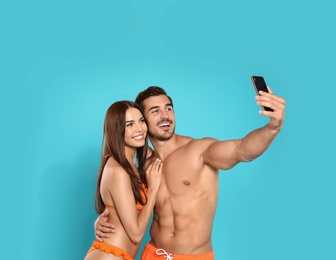 Photo of Young attractive couple in beachwear taking selfie on blue background