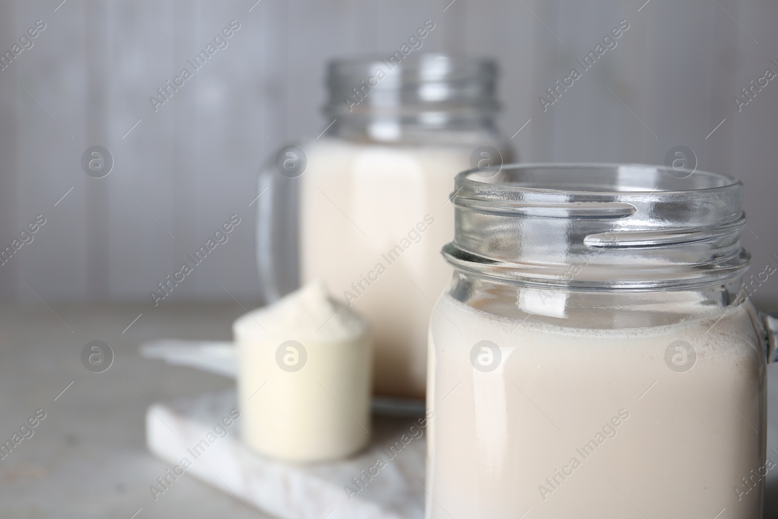 Photo of Mason jar with protein shake on table, closeup. Space for text