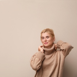 Happy woman in stylish sweater on beige background. Space for text