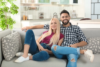 Photo of Young couple watching TV on sofa at home