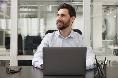 Photo of Man working on laptop at black desk in office