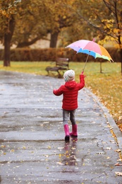 Photo of Little girl with umbrella taking walk in autumn park on rainy day