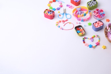 Photo of Kid's handmade beaded jewelry and different supplies on white background. Space for text