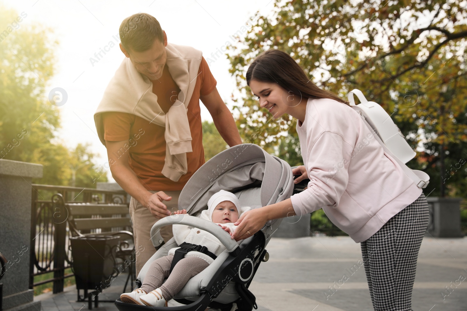 Photo of Happy parents walking with their adorable baby in stroller outdoors