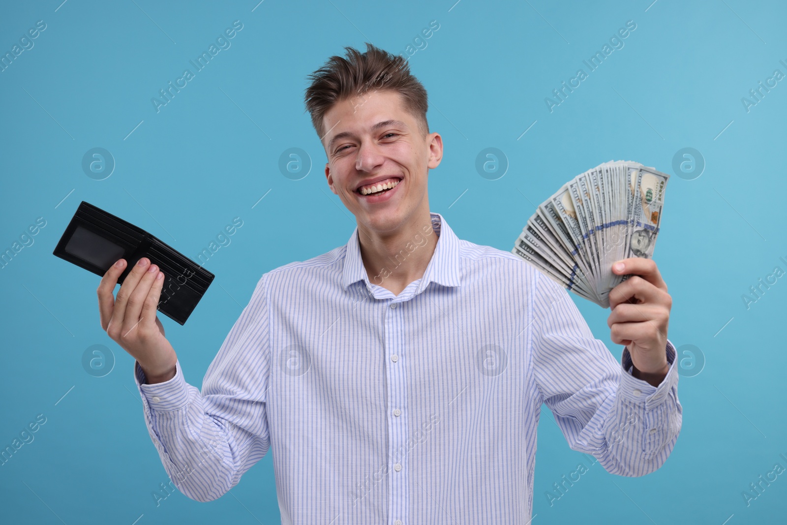 Photo of Happy man with wallet and dollar banknotes on light blue background