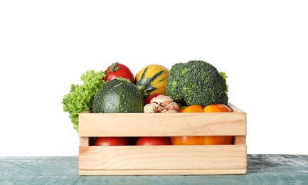 Photo of Wooden crate full of delicious fresh vegetables on table against white background