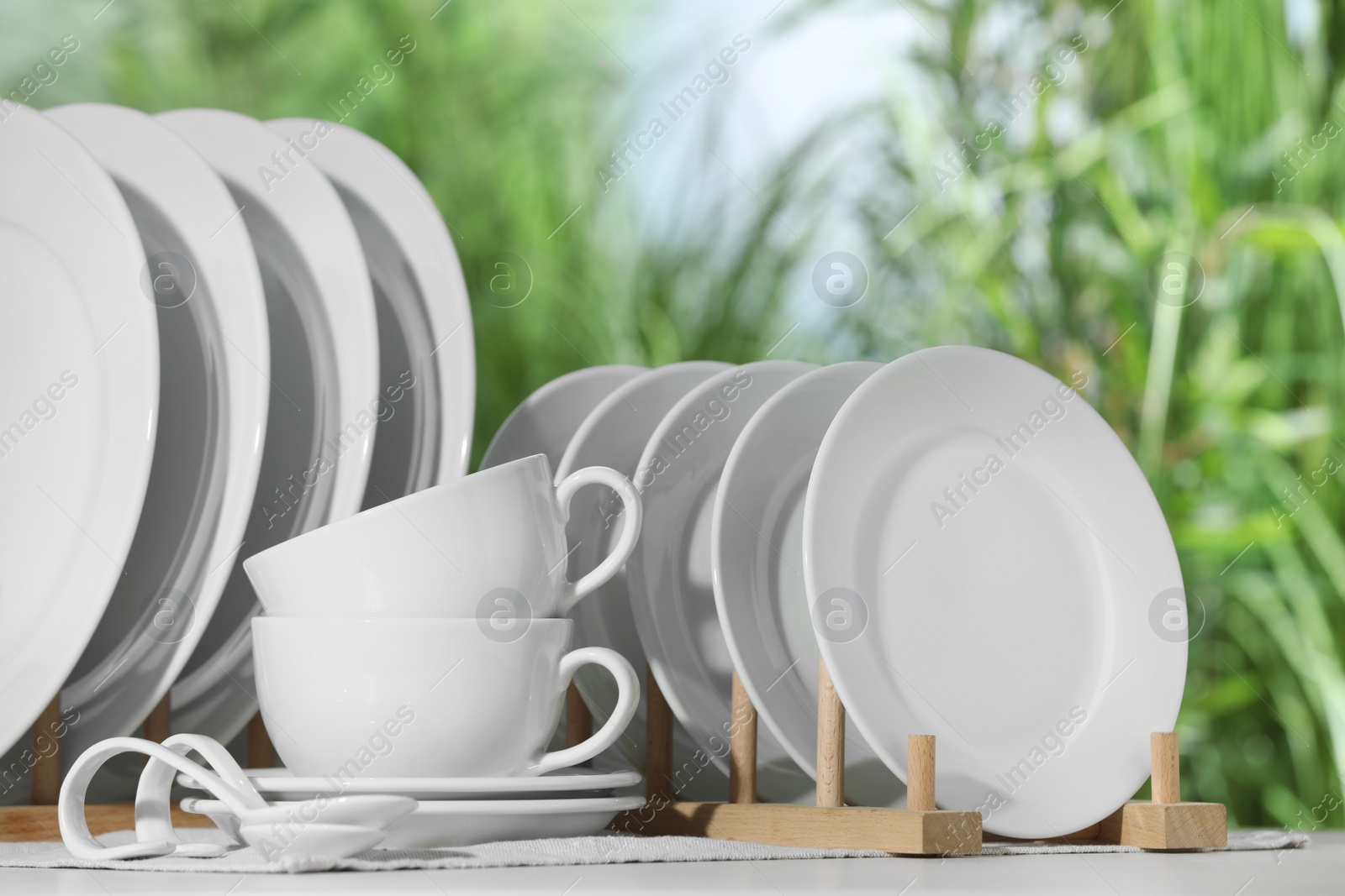 Photo of Set of clean dishware on white table against blurred background