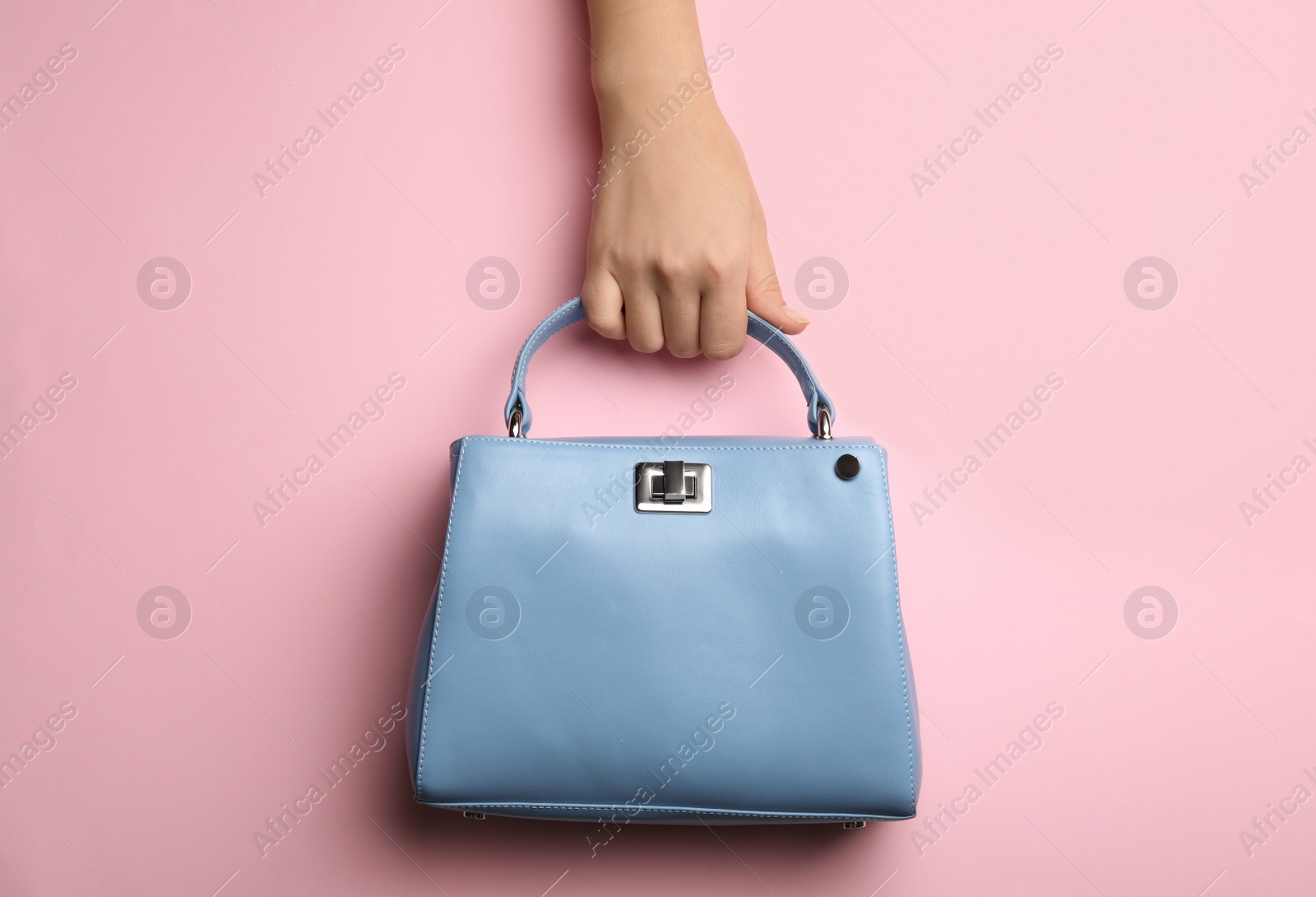 Photo of Woman holding small bag on pink background, top view