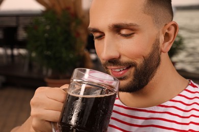 Photo of Man drinking dark beer in outdoor cafe, closeup