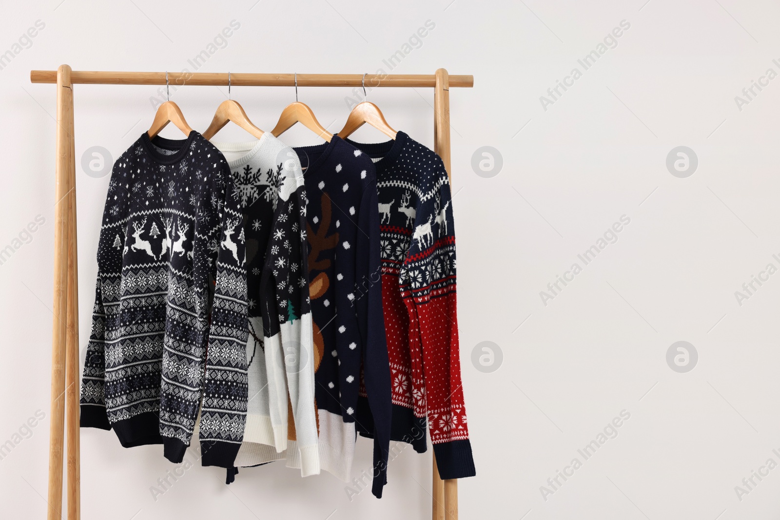 Photo of Rack with different Christmas sweaters on white background, space for text