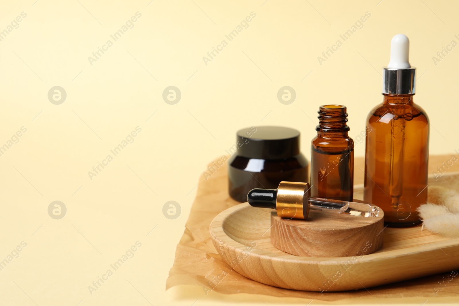 Photo of Composition with bottles of cosmetic serum on beige background. Space for text