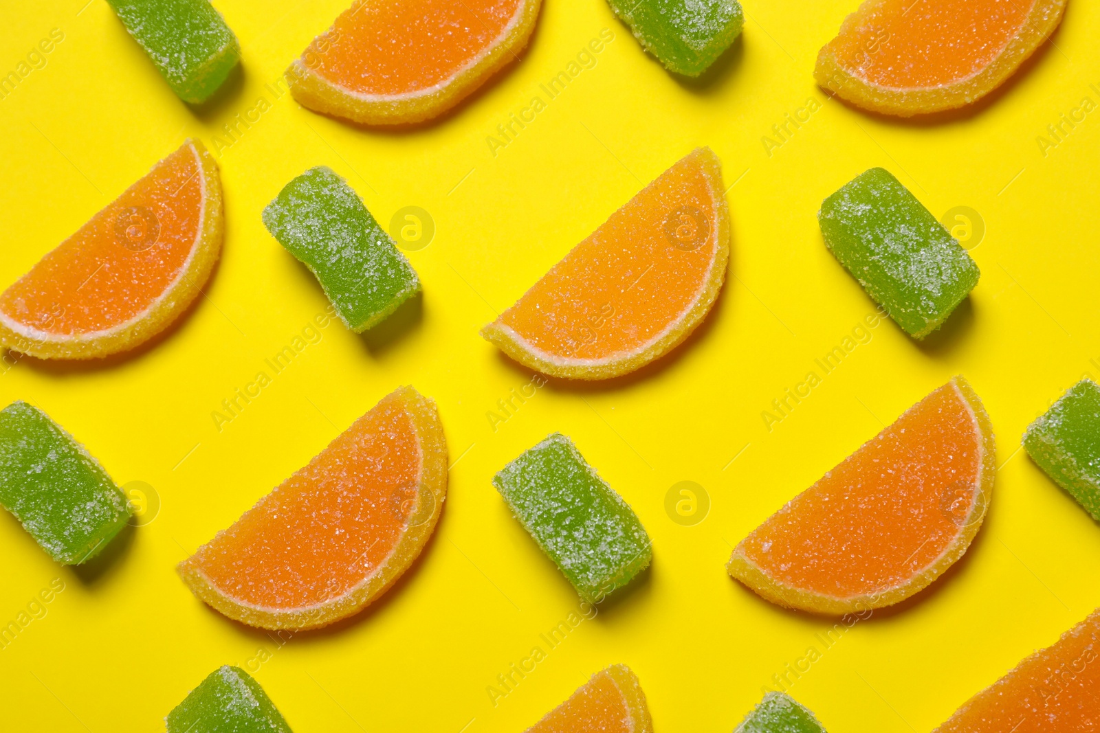 Photo of Tasty jelly candies on yellow background, flat lay
