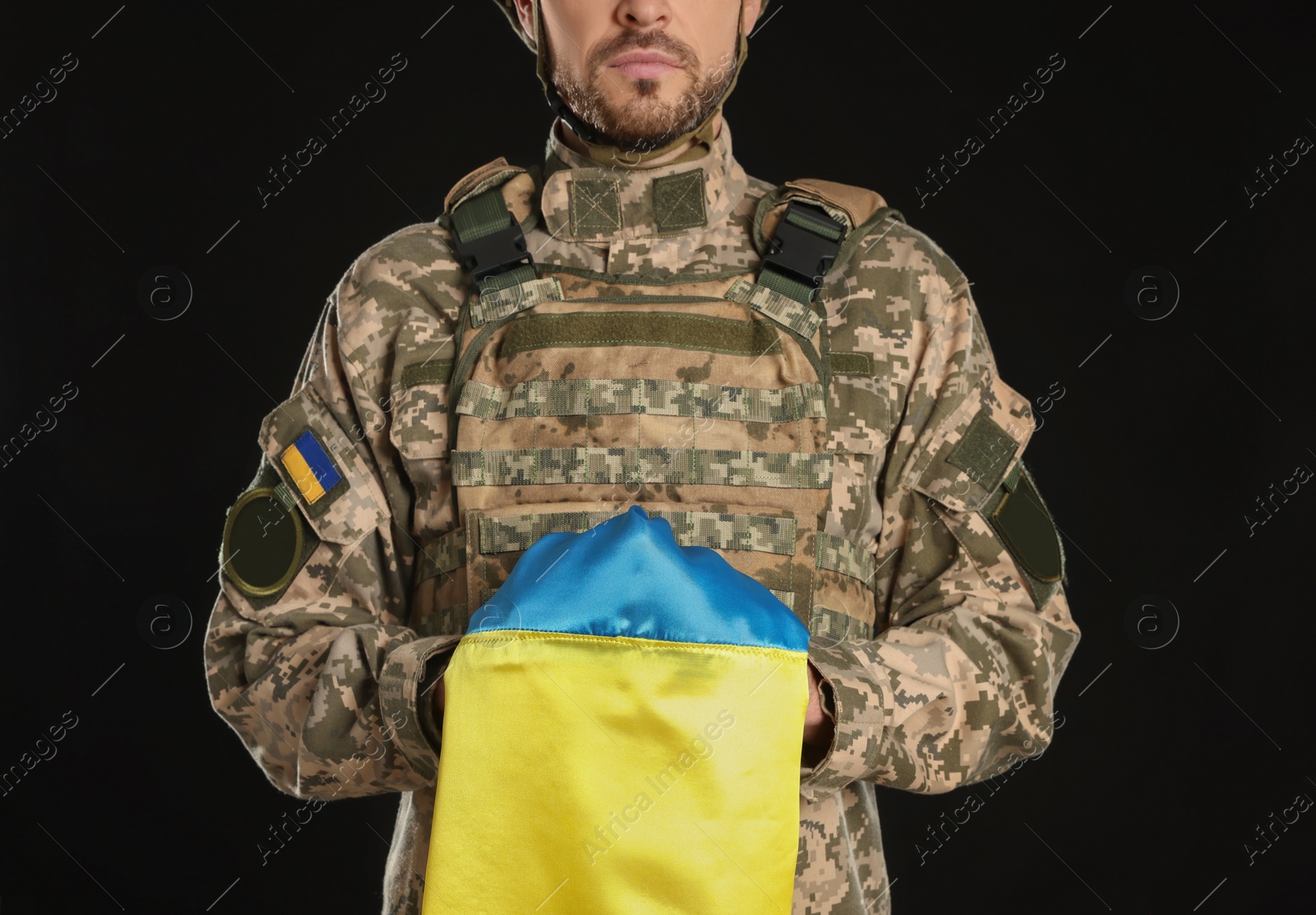 Photo of Soldier in military uniform with Ukrainian flag on black background, closeup