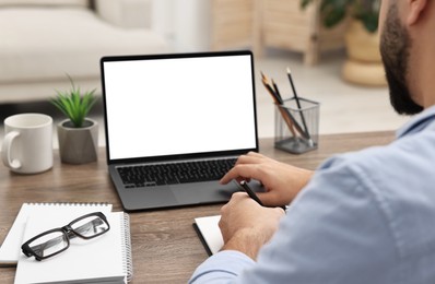 Photo of E-learning. Young man using laptop at wooden table indoors, closeup