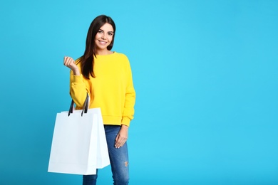 Photo of Portrait of young woman with paper bags on blue background. Space for text