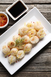 Photo of Raw scallops with spices, dill, lemon zest and sauces on wooden table, flat lay