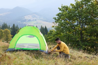 Photo of Man setting up camping tent in mountains