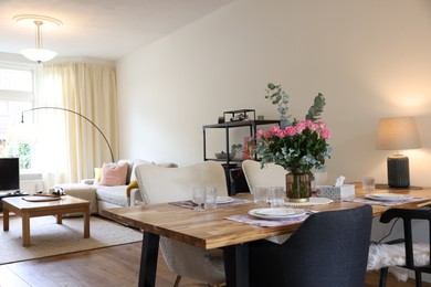 Beautiful table setting with bouquet in dining room. Roses and eucalyptus branches in vase