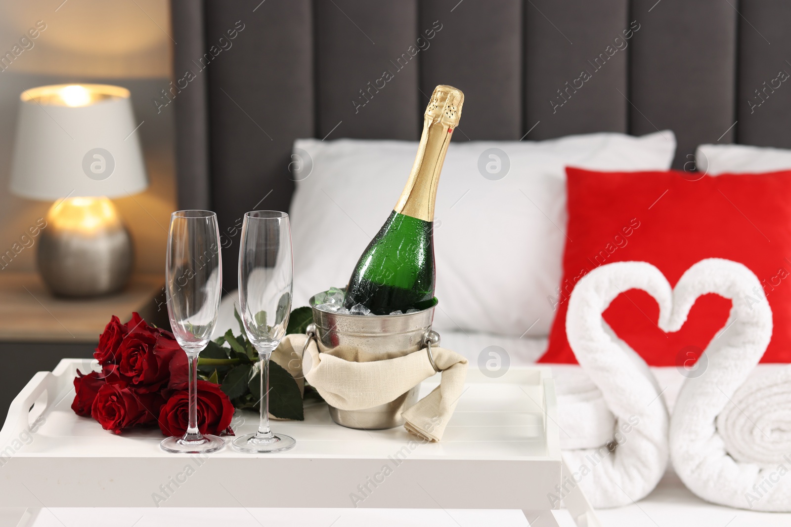 Photo of Honeymoon. Sparkling wine, glasses and bouquet of roses on table in room