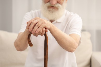 Photo of Senior man with walking cane on sofa indoors, closeup