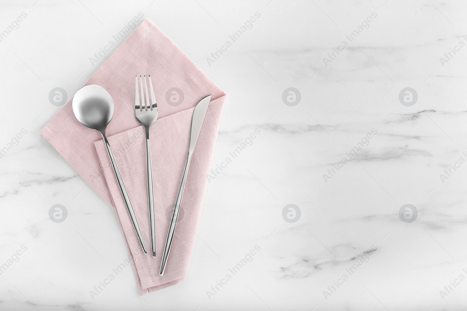 Photo of Stylish cutlery set and napkin on white marble table, flat lay. Space for text