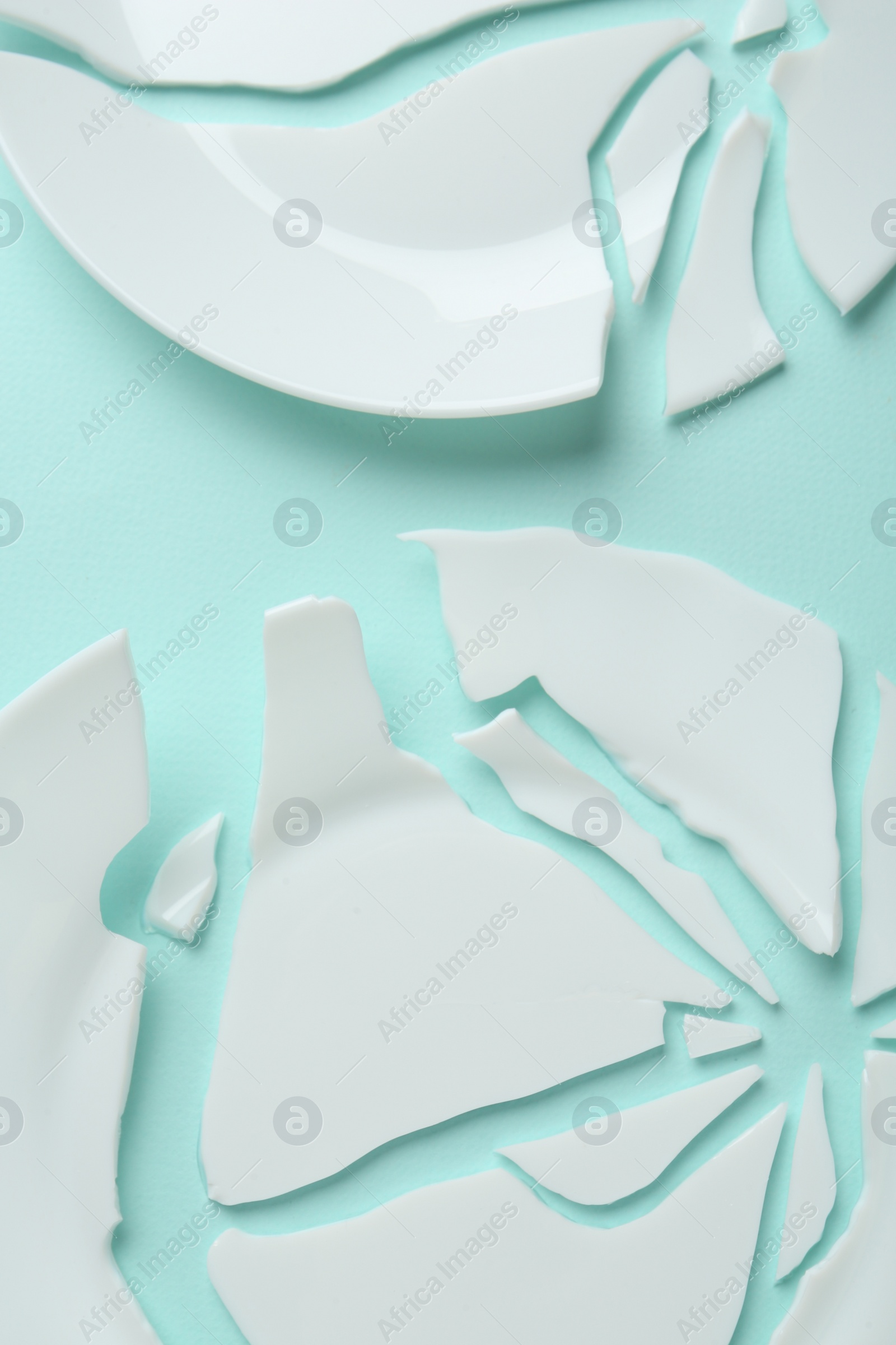 Photo of Two broken ceramic plates on light blue background, flat lay