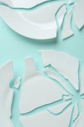 Photo of Two broken ceramic plates on light blue background, flat lay