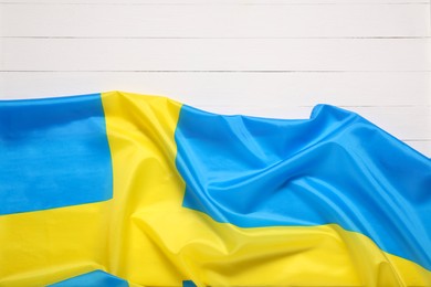 Photo of Flag of Sweden on white wooden background, top view. Space for text