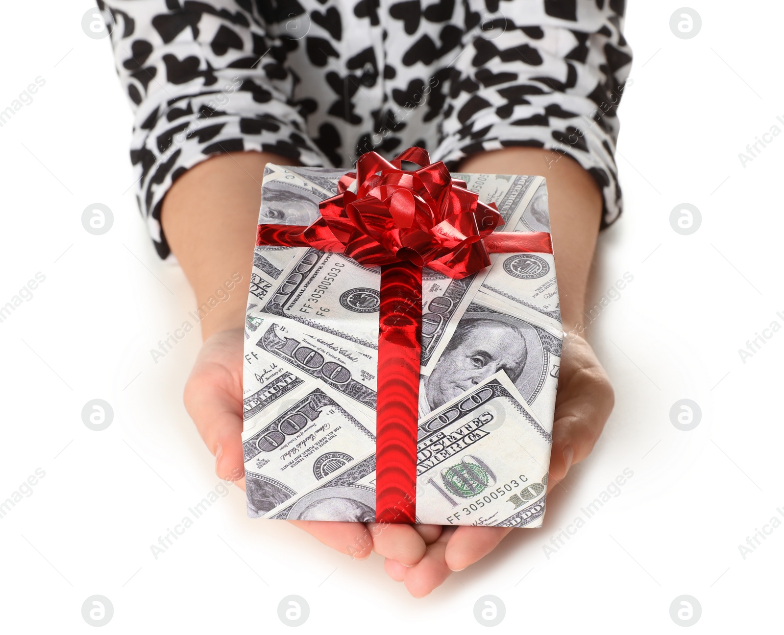 Photo of Woman holding gift box wrapped in decorative paper with dollar pattern on white background, closeup