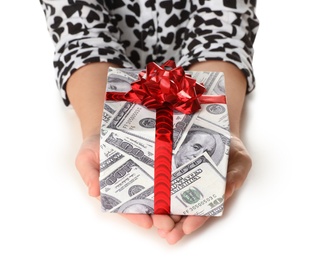 Woman holding gift box wrapped in decorative paper with dollar pattern on white background, closeup