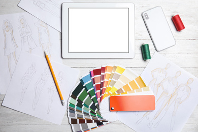 Photo of Workplace of fashion designer with color palette samples and tablet, flat lay