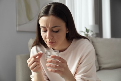 Photo of Young woman with abortion pill and water indoors