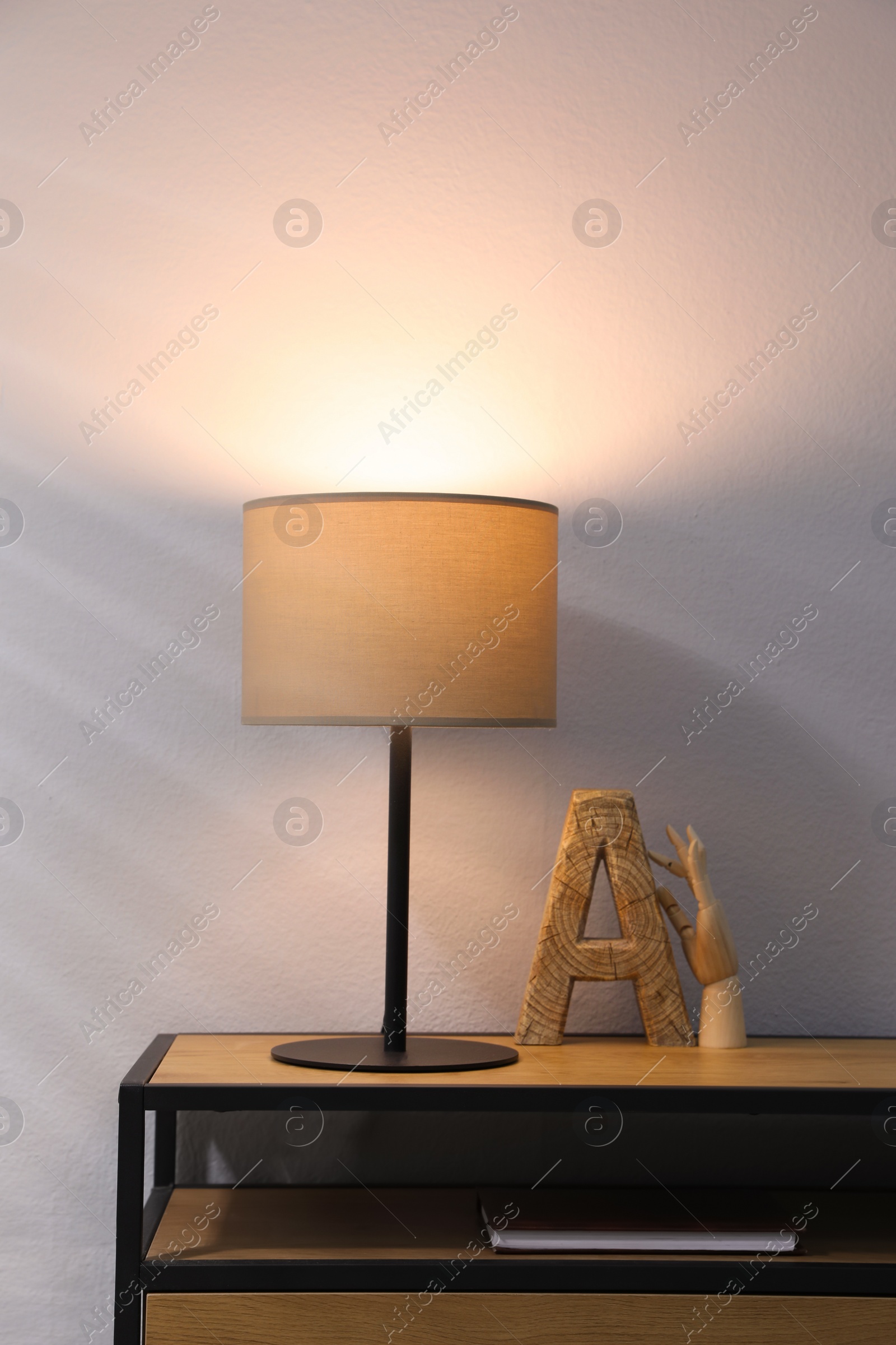 Photo of Stylish lamp and decor on wooden cabinet indoors. Interior design