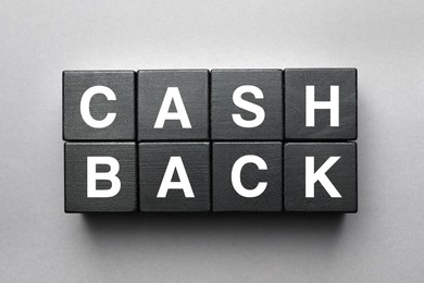 Word Cashback made with black wooden cubes on grey background, flat lay