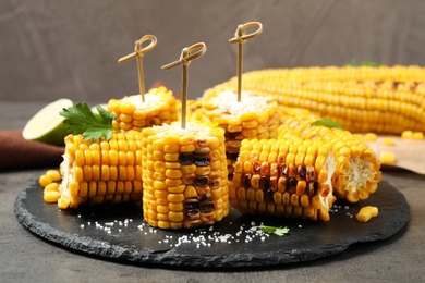 Photo of Composition with tasty grilled corn on grey table