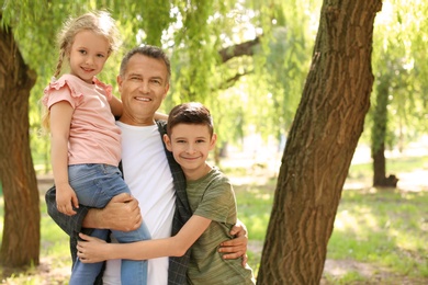 Male pensioner with grandchildren in park. Space for text