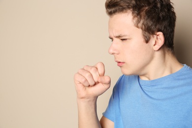 Photo of Teenage boy suffering from cough on color background. Space for text