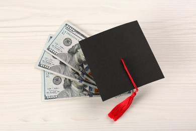 Photo of Scholarship concept. Graduation cap and banknotes on white wooden table, above view
