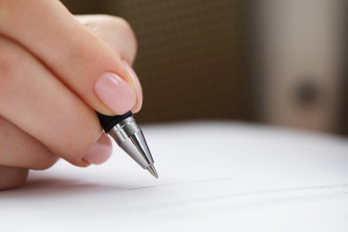 Photo of Woman signing documents indoors, closeup. Space for text