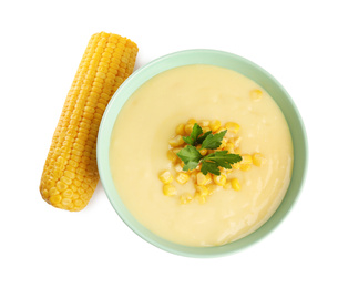 Delicious corn cream soup and cob on white background, top view