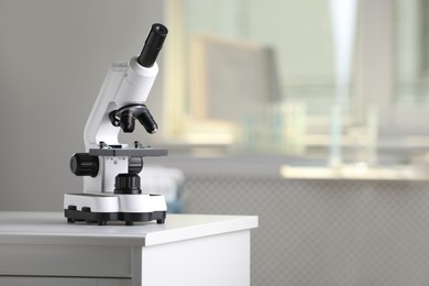 Photo of Modern medical microscope on lab drawer indoors, space for text. Laboratory equipment