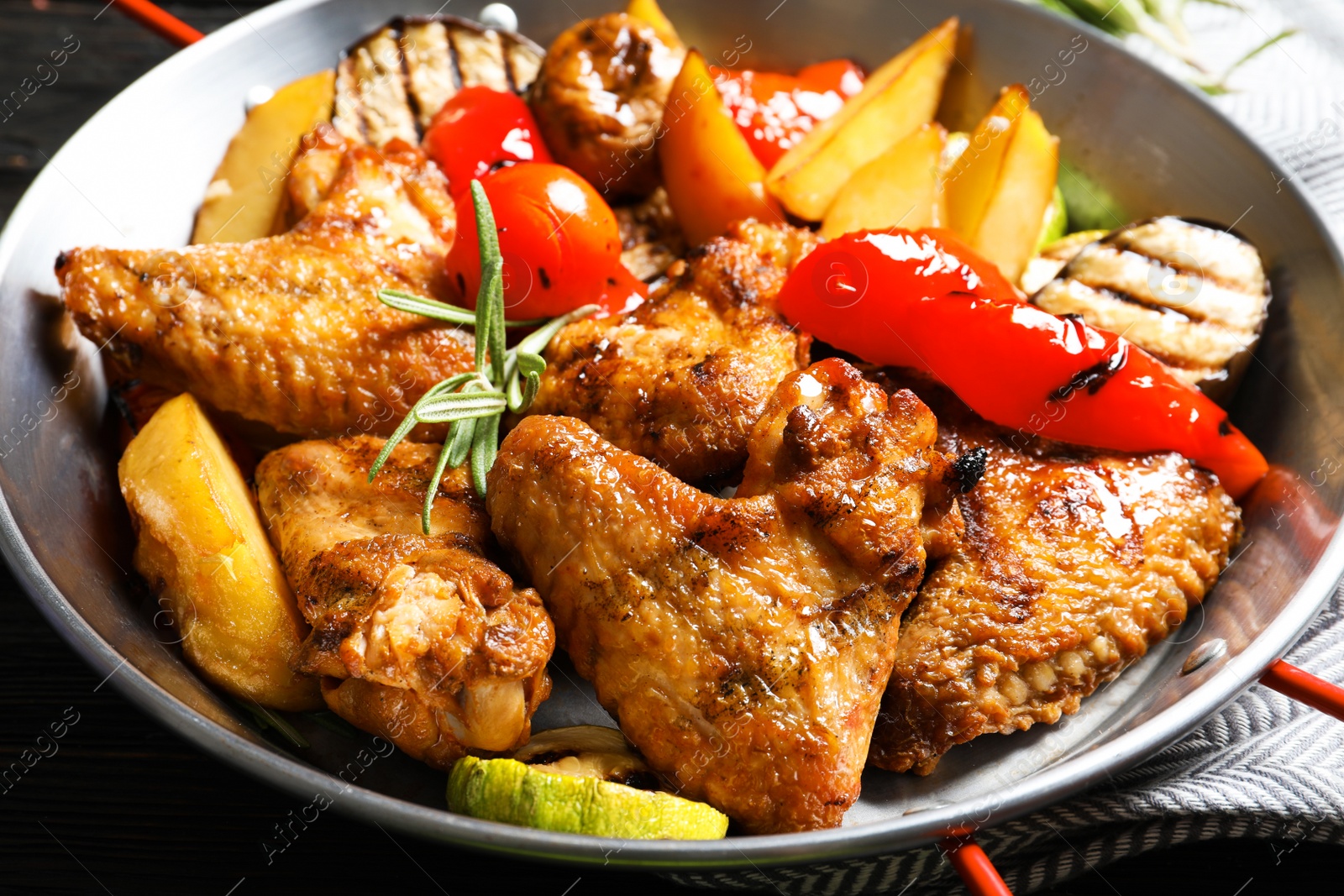 Photo of Delicious barbecued chicken wings with garnish served in wok, closeup