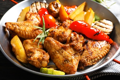 Photo of Delicious barbecued chicken wings with garnish served in wok, closeup